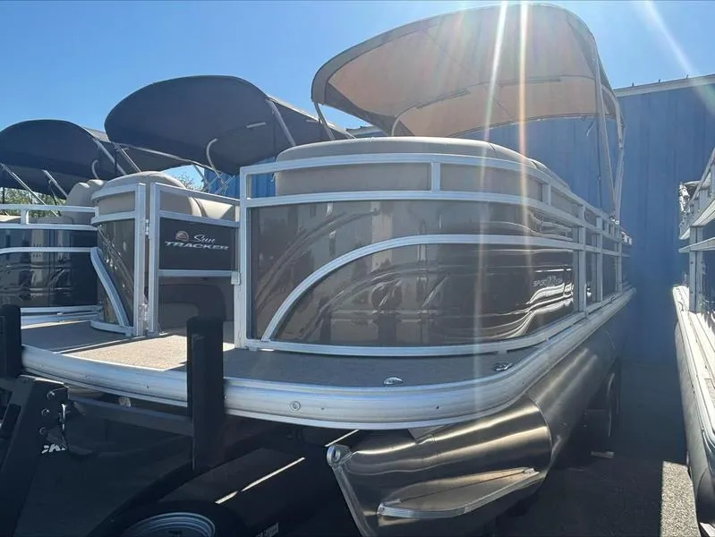 The Image of 2025 Sun Tracker SportFish™ 22 DLX pontoon boat with canopy, parked outdoors. - 0