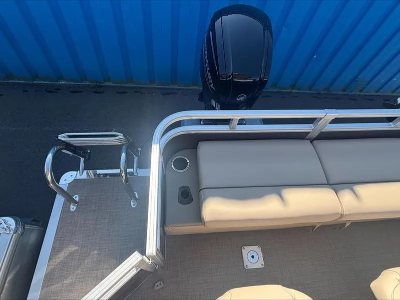 Slide: The Image of 2025 Sun Tracker SportFish™ 22 DLX pontoon boat with seating and motor, docked by blue wall. - 5