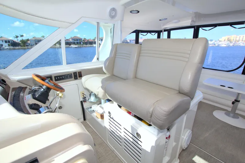 Slide: The Image of 2003 Sea Ray 480 Motor Yacht interior with helm and seating, overlooking waterfront homes. - 25