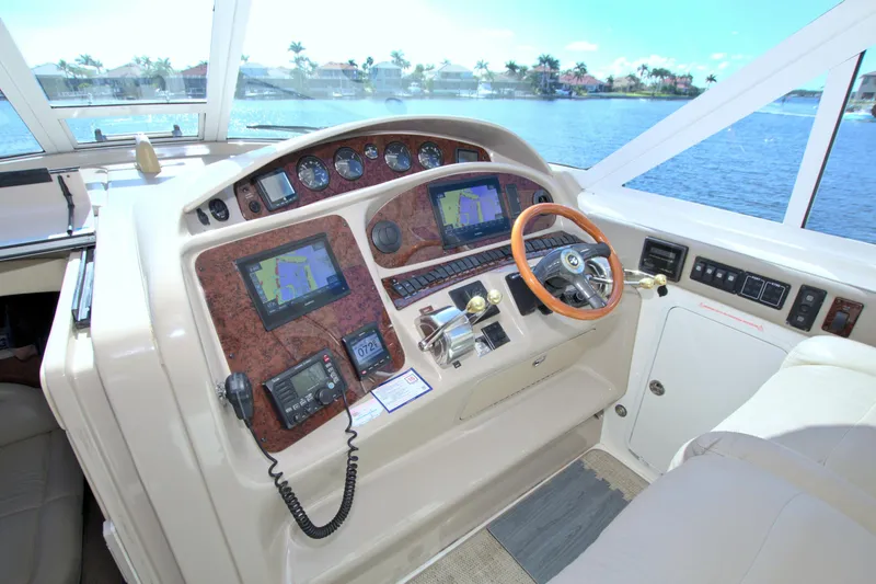Slide: The Image of 2003 Sea Ray 480 Motor Yacht helm with navigation screens and wooden steering wheel. - 26