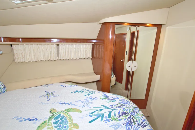 Slide: The Image of Interior of 2003 Sea Ray 480 Motor Yacht with floral bedding and wooden accents. - 48