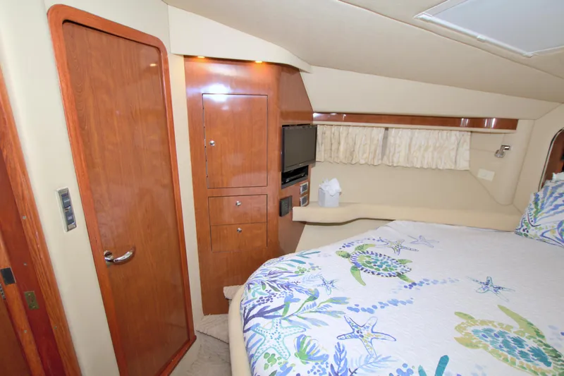 Slide: The Image of Luxurious 2003 Sea Ray 480 Motor Yacht bedroom with wooden cabinetry and nautical-themed bedding. - 49