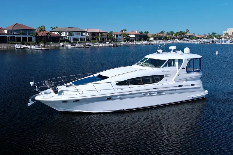 Slide: The Image of 2003 Sea Ray 480 Motor Yacht on calm water, with waterfront homes in the background. - 81
