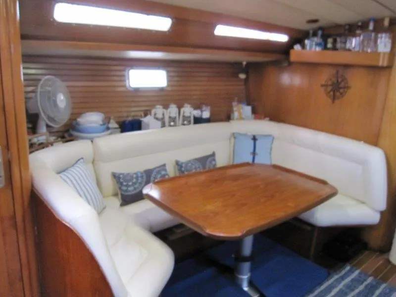 Slide: The Image of Cozy interior of 1990 Jeanneau Sun Magic 44 yacht with wooden table and cushioned seating. - 11