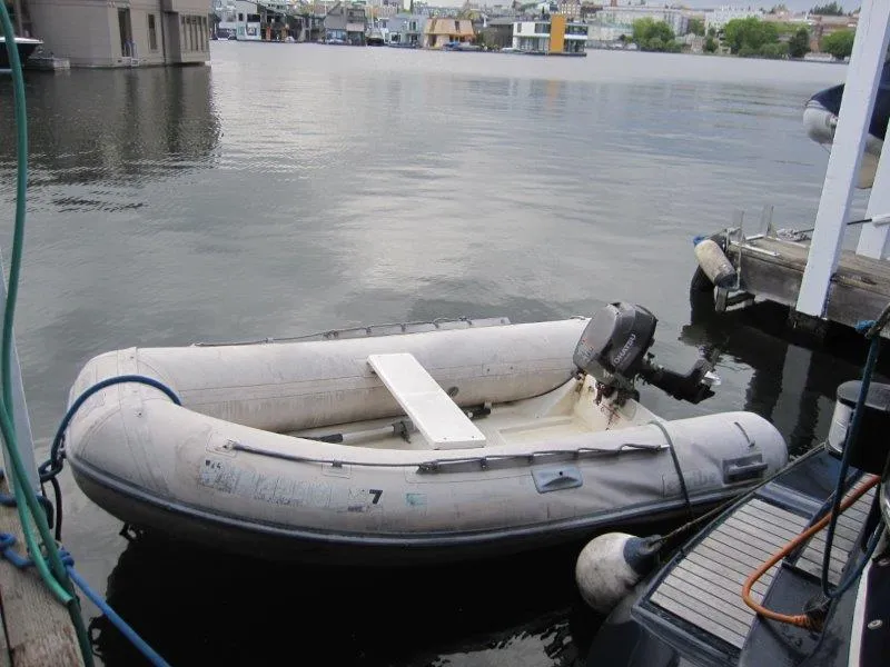 Slide: The Image of Inflatable dinghy with outboard motor docked on calm water. - 39