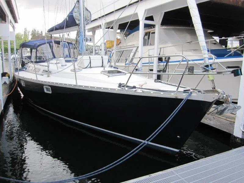 Slide: The Image of 1990 Jeanneau Sun Magic 44 sailboat docked in a marina, featuring a sleek black hull. - 48