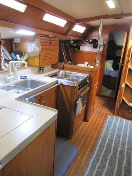 Slide: The Image of Jeanneau Sun Magic 44 yacht interior, featuring a well-equipped kitchen and cozy wooden design. - 5