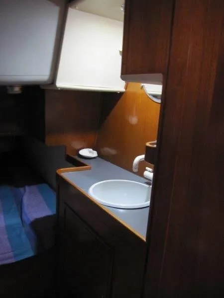 Slide: The Image of Interior of 1990 Jeanneau Sun Magic 44 yacht, featuring a compact sink and wooden cabinetry. - 8