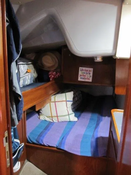 Slide: The Image of Cozy cabin interior of 1990 Jeanneau Sun Magic 44 sailboat with striped bedding and storage. - 9