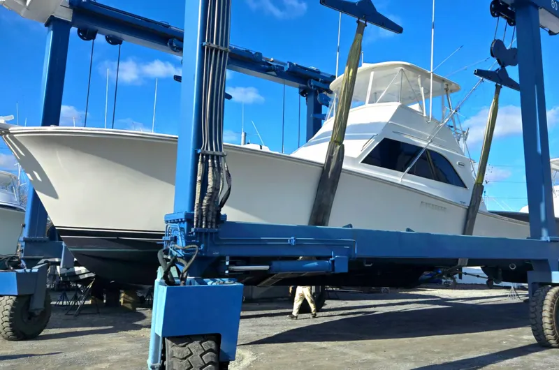 Slide: The Image of 1984 Ocean Yachts 46 Super Sport docked at a marina, with waterfront homes in the background. - 4