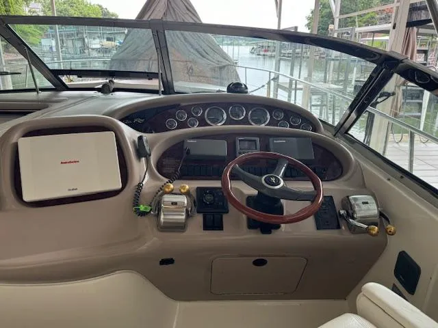 Slide: The Image of 1999 Sea Ray 38' Sundancer helm with steering wheel, gauges, and navigation equipment. - 12