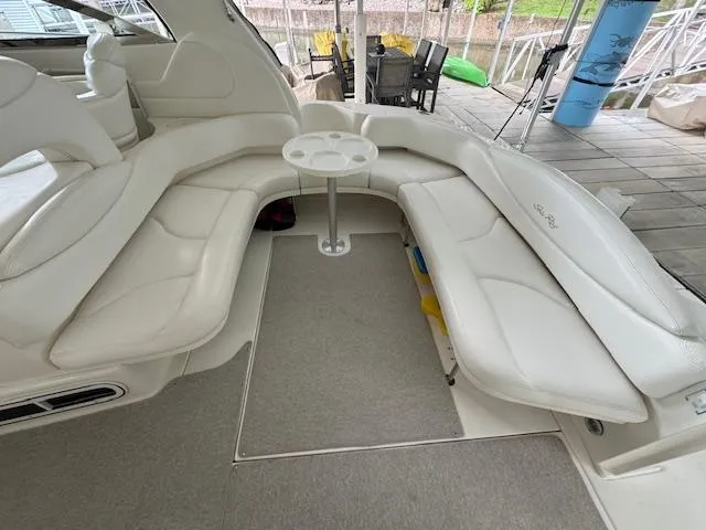 Slide: The Image of 1999 Sea Ray 38' Sundancer interior with white seating and table on a docked boat. - 18