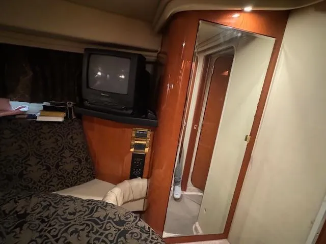 Slide: The Image of 1999 Sea Ray 38' Sundancer cabin interior with TV, mirror, and patterned seating. - 42