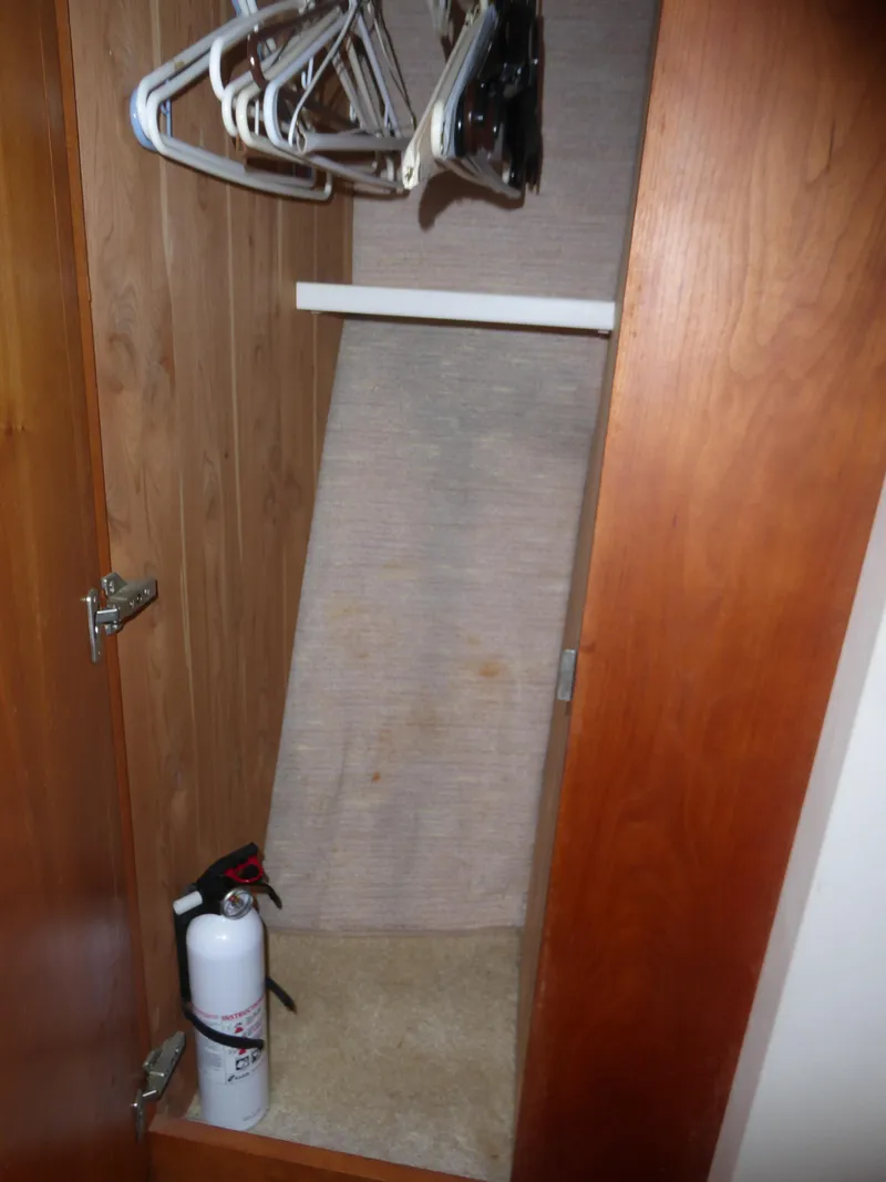 Slide: The Image of Empty wooden closet with hangers and a fire extinguisher, inside a 2000 Silverton 42C Cummins yacht. - 32
