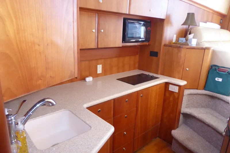 Slide: The Image of 2000 Silverton 42C Cummins yacht kitchen with wood cabinets, sink, and microwave. - 26
