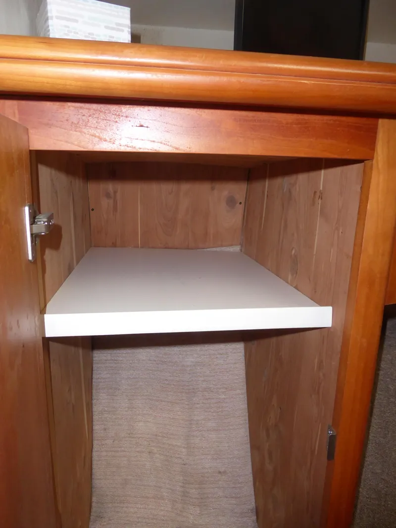Slide: The Image of Wooden cabinet interior with a white shelf, part of a 2000 Silverton 42C Cummins yacht. - 33