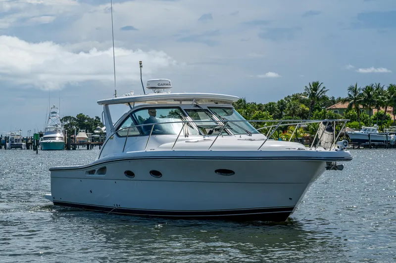 Slide: The Image of 2008 Tiara Yachts 3200 Open cruising on a sunny day, surrounded by lush greenery. - 2