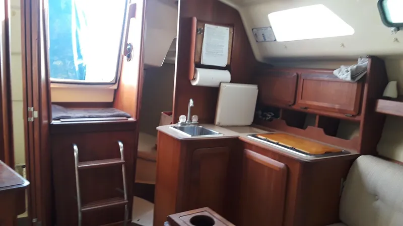 Slide: The Image of Interior of a 1990 Hunter 28 sailboat with wooden cabinetry and compact kitchen area. - 11