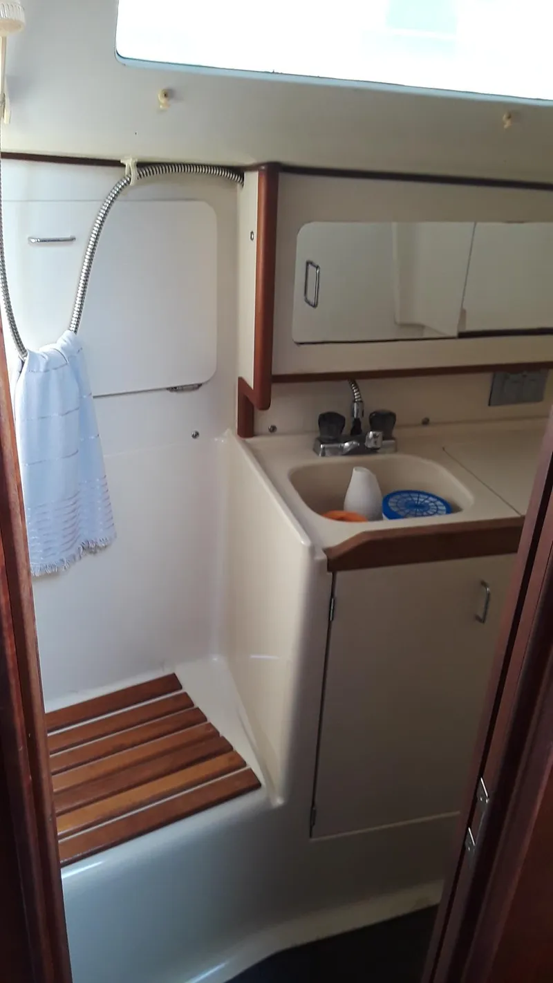 Slide: The Image of 1990 Hunter 28 sailboat bathroom with sink, mirror, and wooden shower seat. - 13