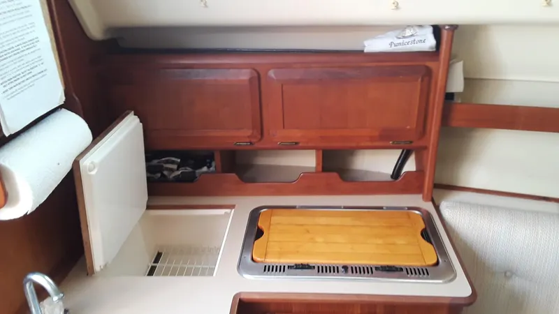 Slide: The Image of Compact kitchen area in a 1990 Hunter 28 sailboat with wooden cabinetry and countertop. - 19