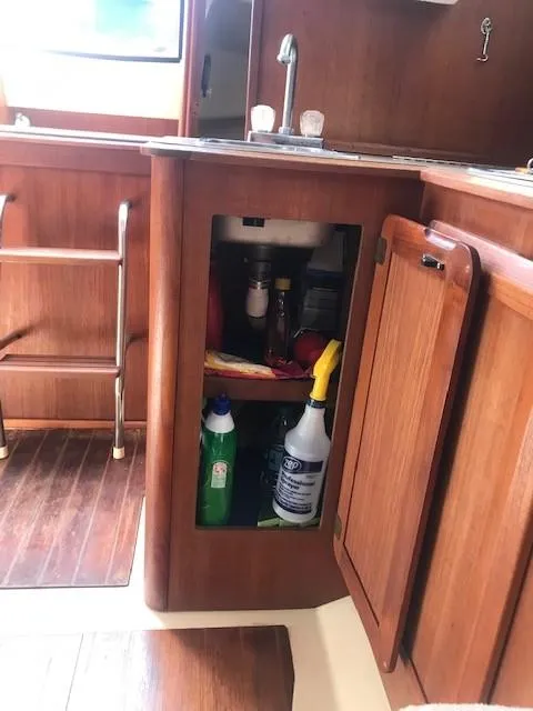 Slide: The Image of 1990 Hunter 28 sailboat interior with open cabinet and cleaning supplies. - 27