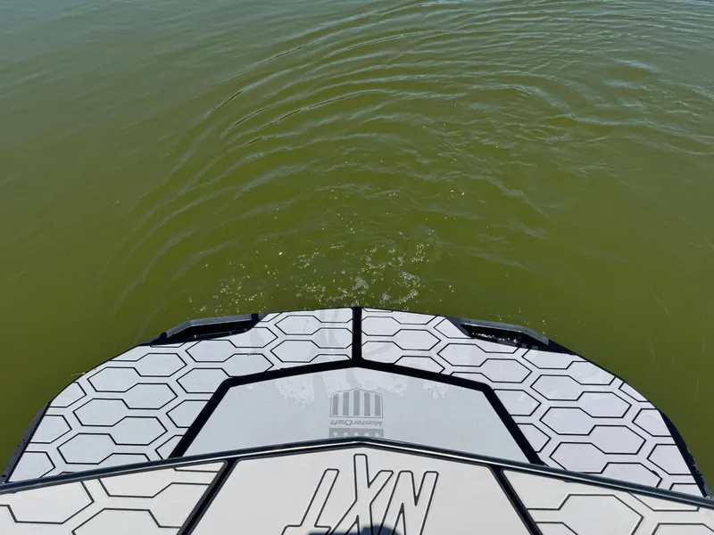 Slide: The Image of 2022 MasterCraft NXT22 boat deck on calm green water. - 22