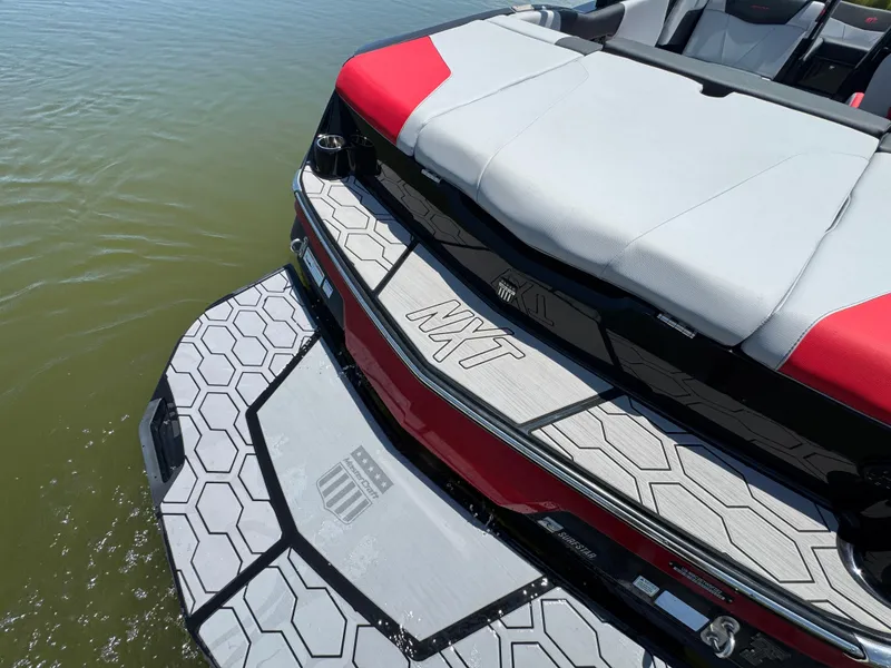 Slide: The Image of 2022 MasterCraft NXT22 boat with stylish seating and hexagonal deck design on the water. - 23