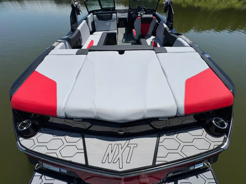 Slide: The Image of 2022 MasterCraft NXT22 boat interior with red and gray seating on calm water. - 24