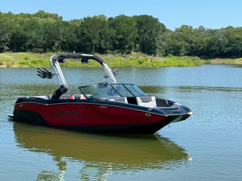 Slide: The Image of 2022 MasterCraft NXT22 boat on a serene lake with lush green surroundings. - 4