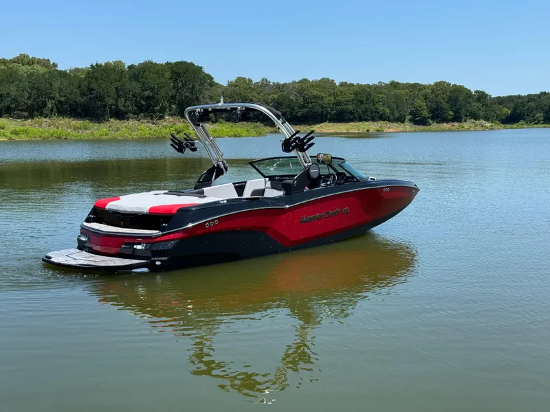 Slide: The Image of 2022 MasterCraft NXT22 boat on a calm lake with lush green shoreline. - 6