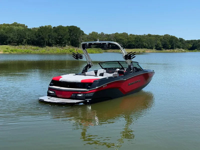 Slide: The Image of 2022 MasterCraft NXT22 boat on a calm lake with lush green surroundings. - 7