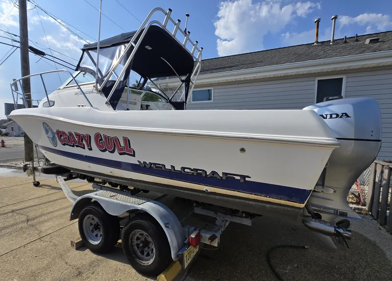 Slide: The Image of 1996 Wellcraft Excel 23 Walk Around boat on trailer, labeled "Crazy Gull," with Honda outboard motor. - 4