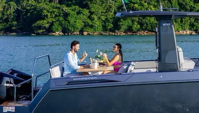 Slide: The Image of Couple enjoying drinks on a 2025 Schaefer V33 yacht, surrounded by scenic water and greenery. - 38