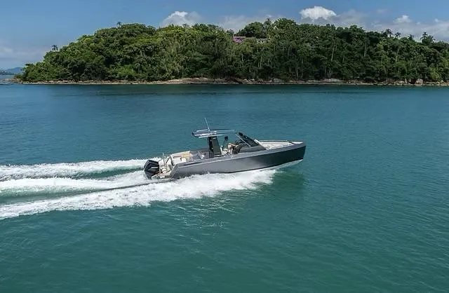 Slide: The Image of 2025 Schaefer V33 boat cruising on blue water near a lush green island. - 1