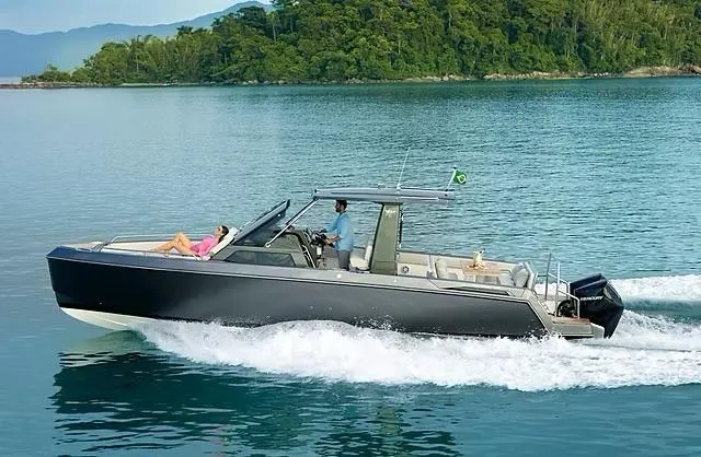 Slide: The Image of 2025 Schaefer V33 boat cruising on serene waters near lush green coastline. - 2