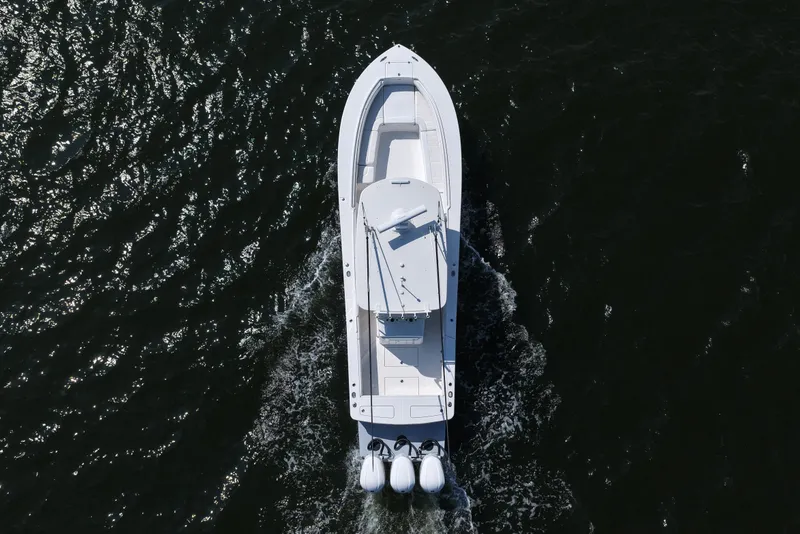 Slide: The Image of 2019 Regulator 34SS boat cruising on a scenic lake with lush green shoreline. - 13