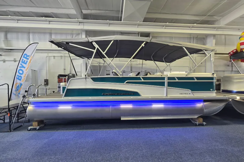The Image of 2025 Princecraft Vectra 23 RL pontoon boat displayed indoors with blue LED lighting. - 0