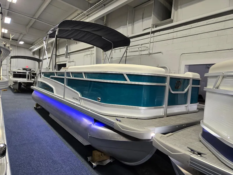 The Image of 2025 Princecraft Vectra 23 RL pontoon boat with blue accents and canopy in showroom. - 1