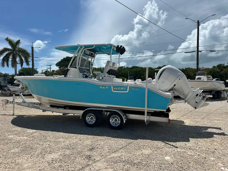 Slide: The Image of 2025 Key West 263 FS boat on trailer, vibrant blue hull, parked outdoors under cloudy sky. - 5