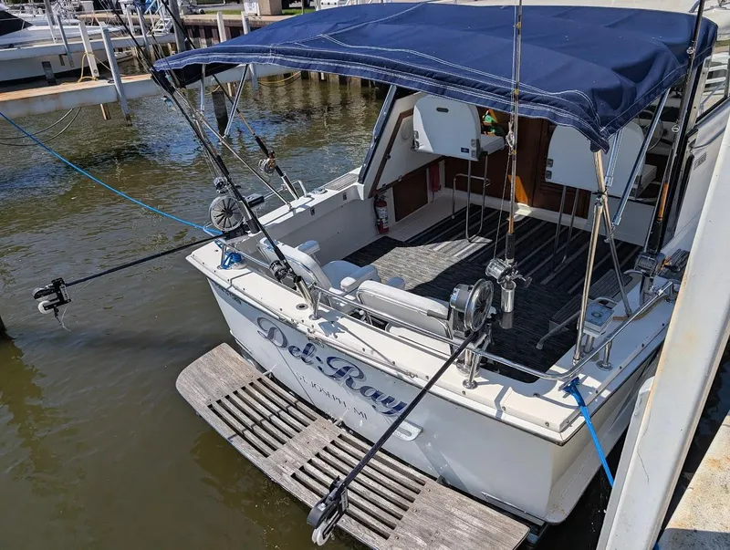 Slide: The Image of 1977 Trojan F30 Express boat docked, featuring fishing rods and a blue canopy. - 10