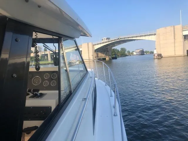 Slide: The Image of 1977 Trojan F30 Express boat navigating under a bridge on a sunny day. - 11