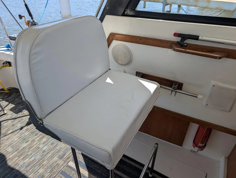 Slide: The Image of Captain's chair on 1977 Trojan F30 Express boat, with white upholstery and nautical interior. - 19