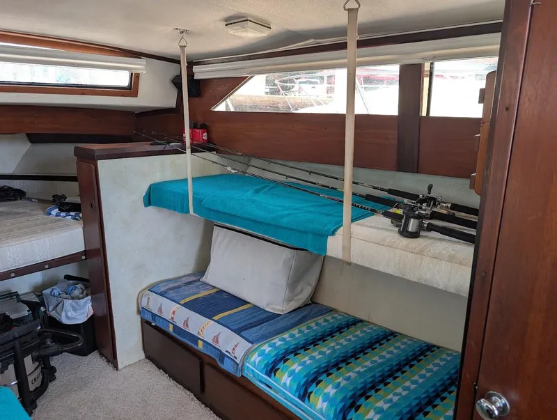 Slide: The Image of 1977 Trojan F30 Express cabin interior with fishing rods and colorful bedding. - 26