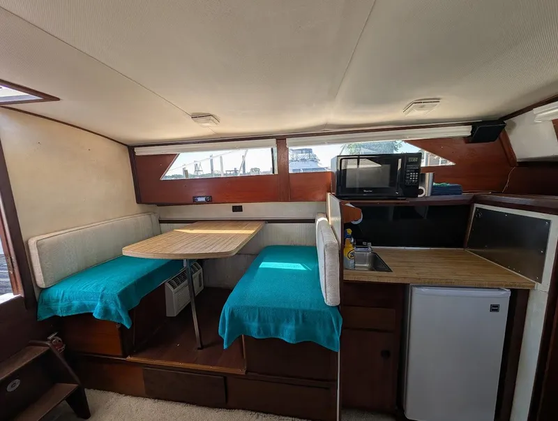 Slide: The Image of 1977 Trojan F30 Express boat interior with dining area, kitchenette, and teal accents. - 27