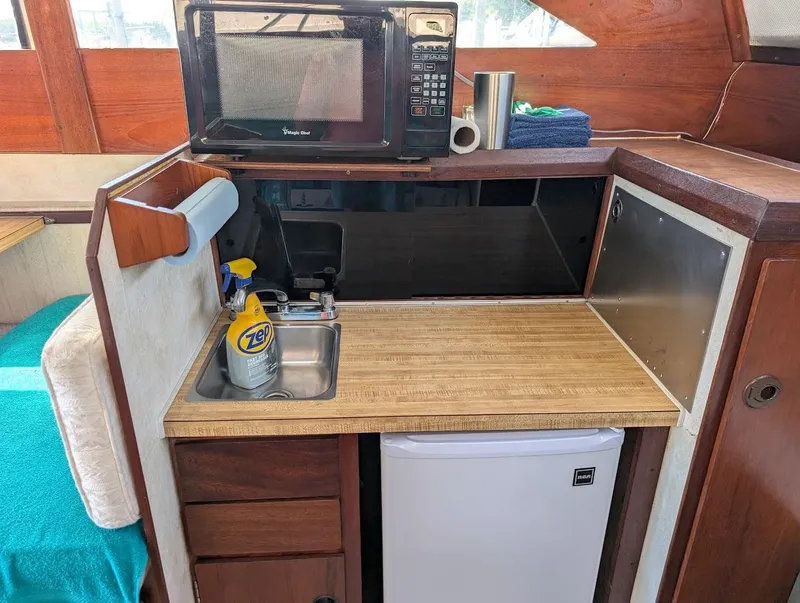 Slide: The Image of 1977 Trojan F30 Express boat kitchenette with sink, microwave, and mini fridge. - 30