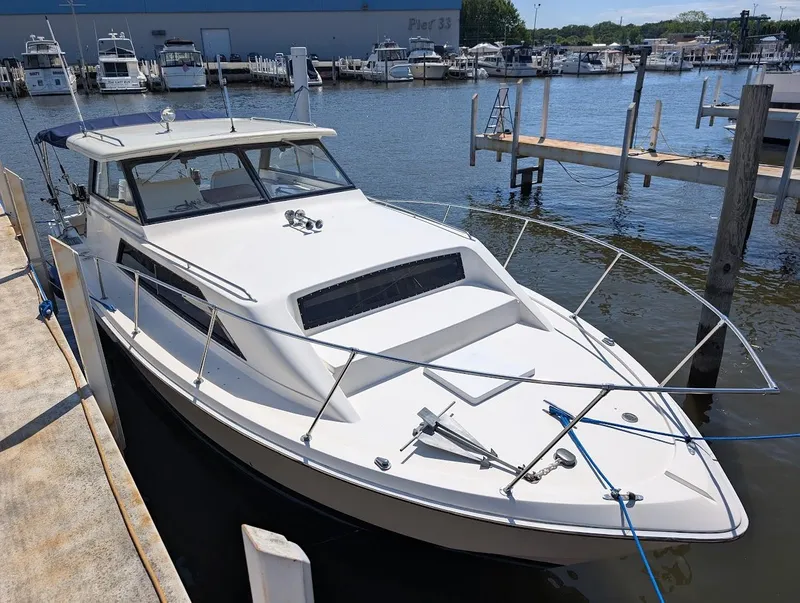 Slide: The Image of 1977 Trojan F30 Express boat docked at marina, surrounded by water and other vessels. - 7