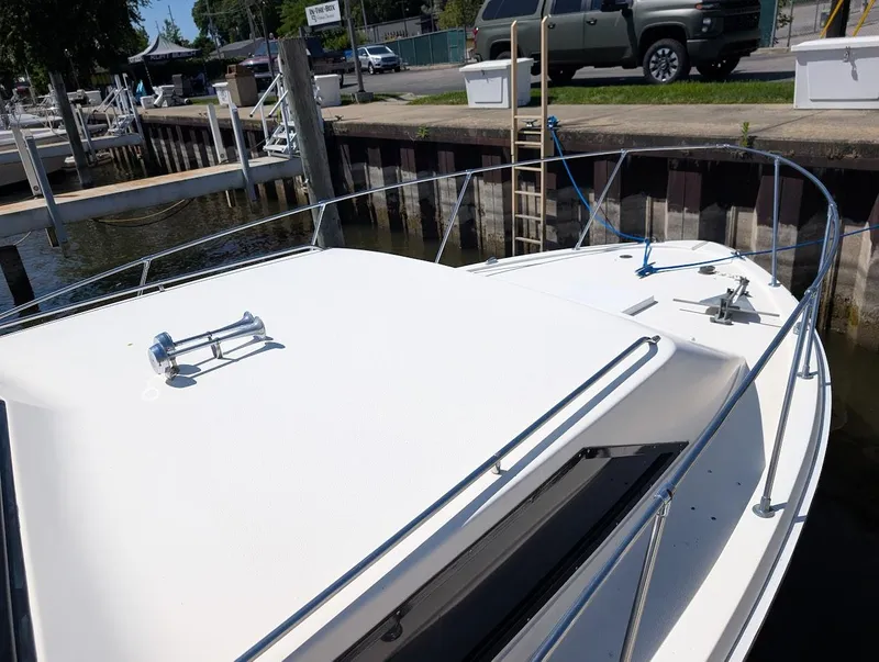 Slide: The Image of 1977 Trojan F30 Express boat docked at marina, featuring sleek white deck and railings. - 8