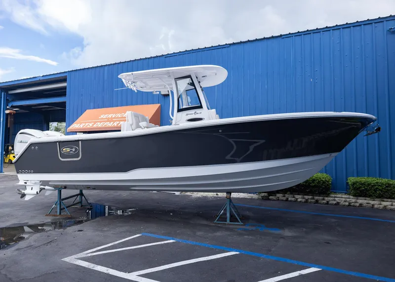 Slide: The Image of 2026 Sea Hunt Gamefish 27 Coffin Box boat at service center, blue building background. - 0