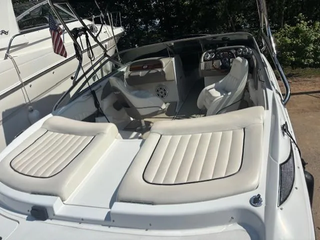 Slide: The Image of 2006 Cobalt 220 boat interior with white seating and dashboard, docked beside another vessel. - 3