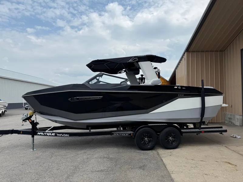 Slide: The Image of 2025 Nautique Super Air Nautique G23 boat on trailer, parked near a building. - 14